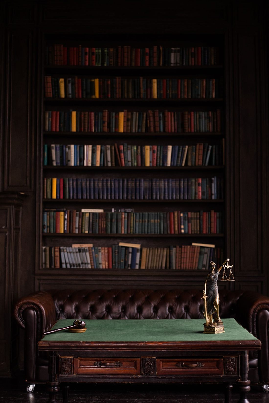 Bibliotecă juridică, cu volume de drept și statueta Justiției